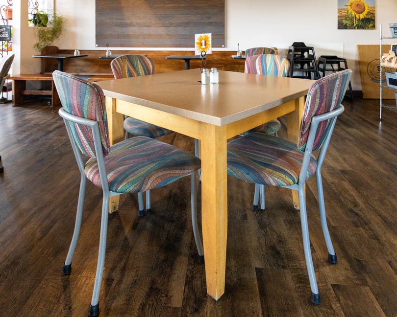 A square wooden table with four chairs featuring colorful striped upholstery in a restaurant dining room.