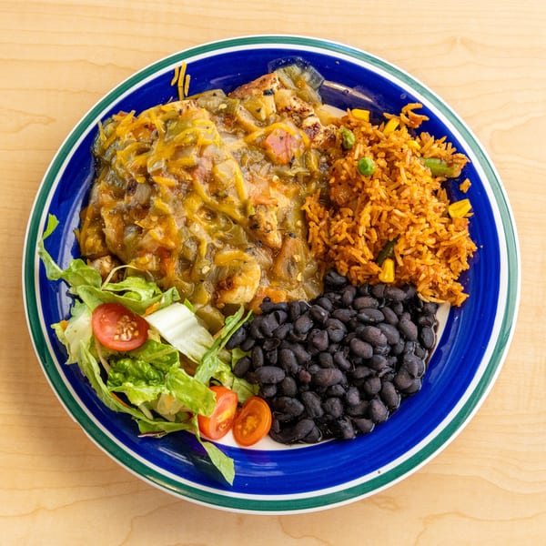 Chicken smothered in green chili sauce with rice, black beans, and a side salad.