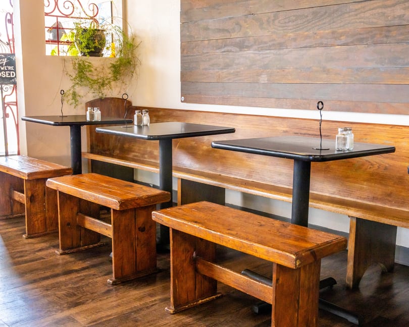 Restaurant interior with dark tables, wooden benches, and a long wooden wall panel.